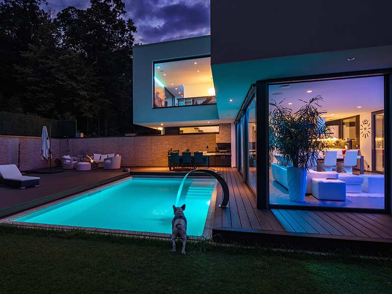 Luxury home exterior with pool lighting at night